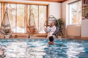 a woman sitting in a chair in a swimming pool at Hotel Jagdhaus Monzabon in Lech am Arlberg