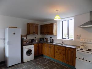 a kitchen with wooden cabinets and a white refrigerator at The Old Creamery Ventry in Ventry