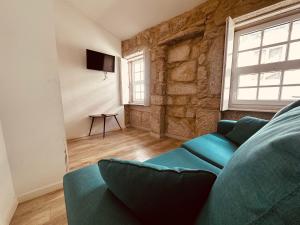a living room with a blue couch and a stone wall at Casa Jardim in Porto