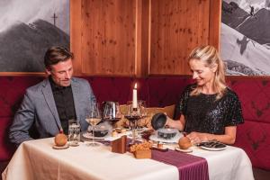a man and woman sitting at a table in a restaurant at Hotel Jagdhaus Monzabon in Lech am Arlberg