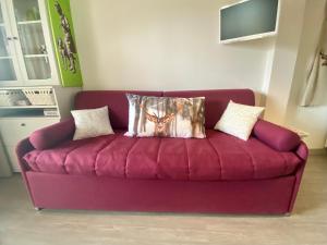 a purple couch with two pillows on top of it at Bright and silent studio in Bardonecchia centre in Bardonecchia