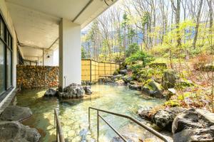 a pond in the middle of a house with rocks at Livemax Resort Hachimantai Forest in Hachimantai