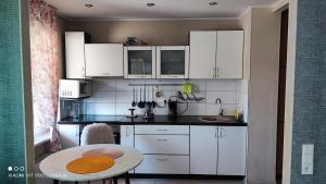 a small kitchen with white cabinets and a table at Liepaja Beach in Liepāja