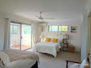 a white bedroom with two beds and a window at "Casa Serena" - Spacious Entire Holiday Home in Caboolture