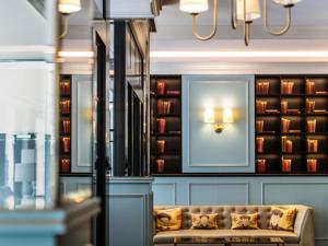 eine Couch in einem Zimmer mit Büchern an der Wand in der Unterkunft Hotel Rotary Geneva - MGallery in Genf