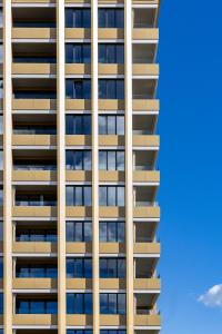 a tall building with a blue sky in the background at Hôtel des Innovations - Hôtel & Appartements - Votre séjour entre Fribourg, ville médiévale et La Gruyère et ses Bains in Marly-le-Grand