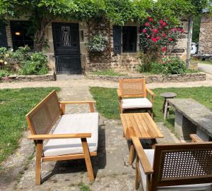 three wooden chairs and a table and a bench at Gîte des vergnioux in Ayat-sur-Sioule
