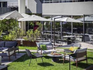 a patio with chairs and tables and umbrellas at Novotel Annecy Centre in Annecy