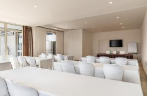 a conference room with white chairs and a flat screen tv at Hotel Regina in Caserta
