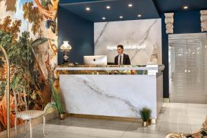 a man standing at a counter with a laptop at Hotel Regina in Caserta