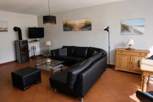 a living room with a black leather couch and a tv at Ferienhaus zum Kranichblick ideal für Familien gern mit Hund in Garz
