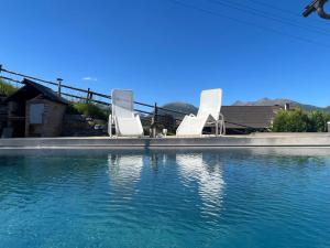 two white chairs sitting on the edge of a swimming pool at AlpenChalet Mitterberg in Mariapfarr