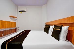 a bedroom with a white bed with black and white pillows at Collection O Bwalk Hotel Malang in Malang