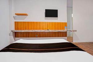 a bedroom with a bed and a tv on the wall at Collection O Bwalk Hotel Malang in Malang +25 photos