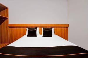 a bedroom with a white bed with black pillows at Collection O Bwalk Hotel Malang in Malang