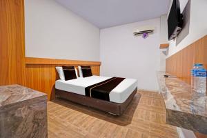 a bedroom with a bed and a television in it at Collection O Bwalk Hotel Malang in Malang