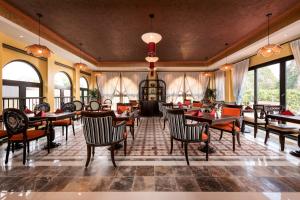 a restaurant with tables and chairs and windows at Tam Coc Holiday Hotel & Spa in Ninh Binh