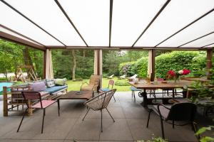 a conservatory with a patio with tables and chairs at Gîte Du Ruisseau avec spa et pêche in Épinal