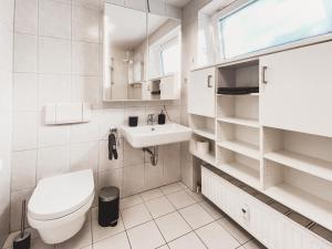 a white bathroom with a toilet and a sink at Casa Bonita in Heikendorf +7 photos