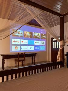 a large screen in a living room with a bench at Villa Balapitiya Beach in Balapitiya