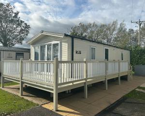 a tiny house with a porch and a white fence at Sycamore Farm Park in Burgh le Marsh
