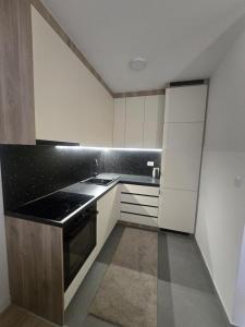 a kitchen with white cabinets and a black stove at CityLux L in Doboj