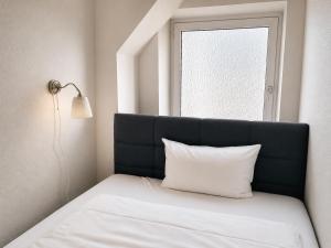 a bed with a black headboard and a white pillow at NOBLE APART Saarbrücken City Center in Saarbrücken
