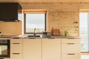 a kitchen with white cabinets and a sink and two windows at Á Varða Apartments in Tórshavn