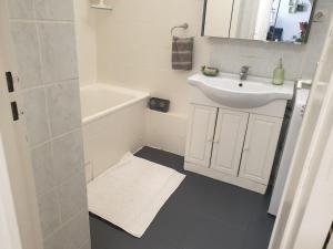 a white bathroom with a sink and a bath tub at Cozy Private Room -5 mins from CERN -Shared Apartment in Saint-Genis-Pouilly