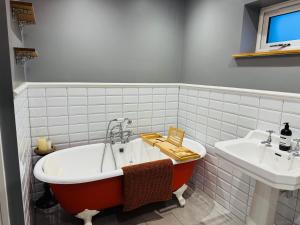 a bathroom with a tub and a sink at The Goods Shed in Narborough +10 photos