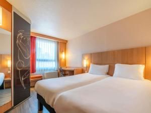 a hotel room with a large bed and a table at ibis Montpellier Centre Polygone in Montpellier +67 photos
