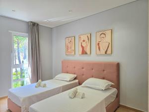 a bedroom with two beds and a pink headboard at White Shell Apartments in Lalzit Bay +52 photos