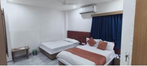 a hotel room with two beds and a window at Hotel Radhe Inn in Gandhinagar