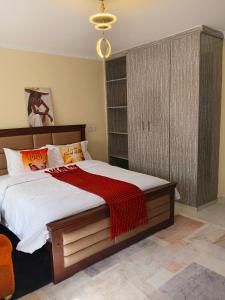 a bedroom with a large bed with a red blanket at Bnb Studio Oasis Homes in Machakos