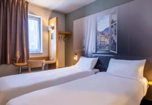 a hotel room with two beds and a desk at B&B HOTEL Annecy Argonay in Argonay