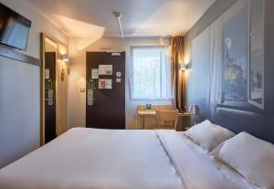 a bedroom with a large white bed and a table at B&B HOTEL AVRANCHES Baie du Mont St-Michel in Le Val-Saint-Père