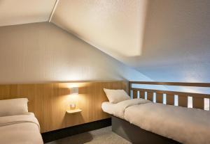 two beds in a room with a sloped ceiling at B&B HOTEL AVRANCHES Baie du Mont St-Michel in Le Val-Saint-Père