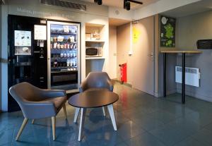 a restaurant with two chairs and a table and a refrigerator at B&B HOTEL AVRANCHES Baie du Mont St-Michel in Le Val-Saint-Père +19 photos