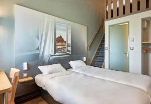 a bedroom with a large bed and a staircase at B&B HOTEL AVRANCHES Baie du Mont St-Michel in Le Val-Saint-Père