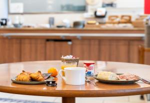 a table with two plates of food and a cup of coffee at B&B HOTEL Lyon Eurexpo Bron in Bron
