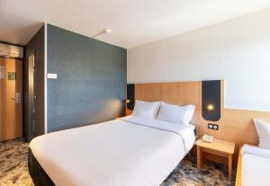 a hotel room with a large white bed in it at B&B HOTEL Lyon Eurexpo Bron in Bron