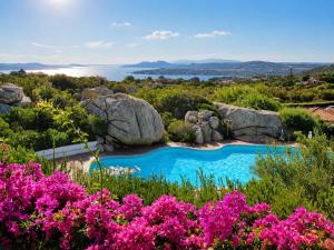 a swimming pool with rocks and pink flowers at NEW 2026 - Villa Rafael in Porto Rafael