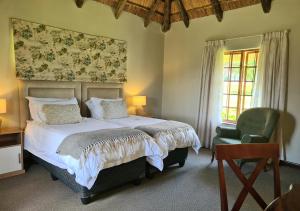 a bedroom with a bed and a green chair at Otters Den in Nottingham Road