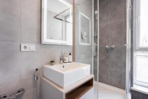 a bathroom with a white sink and a shower at Nyvky Like Home - Studio - apt 35 in Kyiv +16 photos
