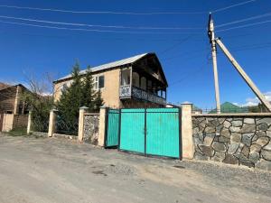 a house with a fence and a stone wall at Guest house Kyial in Naryn
