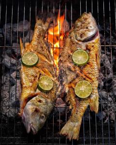 two fish on a grill with lime slices on them at Handhuvaru Maldives in Milandu +89 photos