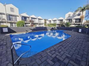 a blue swimming pool in a courtyard with houses at warm, quiet and convenient ! in Auckland