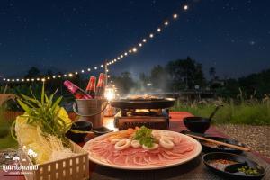 a table with a plate of food and a grill at หินผาปัว รีทรีต & หินผาโฮมสเตย์ in Ban Choko