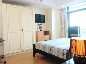 ein Schlafzimmer mit Bett und Flachbildfernseher in der Unterkunft Baywatch Tower in Manila