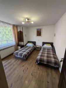 two beds in a room with wooden floors at Zatishok Guest House in Rakhiv